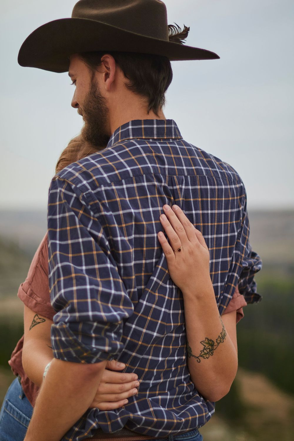 Outdoor couples photoshoot with a man wearing a cowboy hat and the woman hugging the man