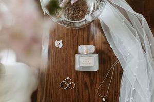 A delicate arrangement of white flowers, veil, and wedding accessories artfully displayed on rustic wooden surfaces.
