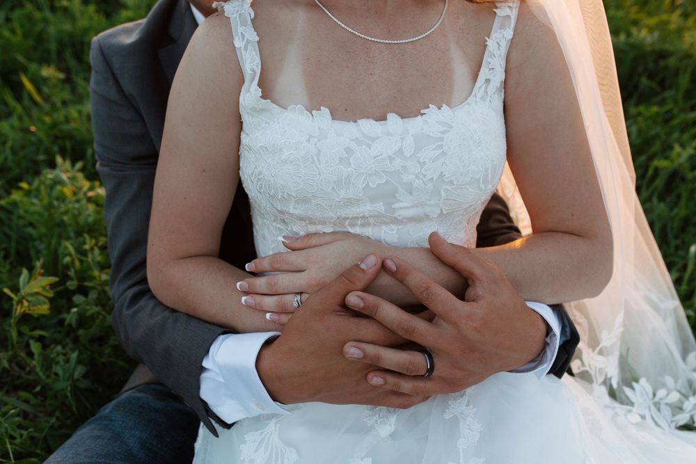 A close-up detail shot of a white lace wedding dress bodice with delicate floral embroidery and spaghetti straps.