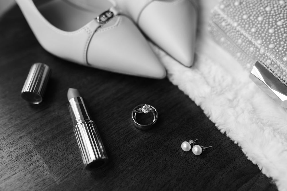 Elegant pearl stud earrings displayed on a white textured surface next to silver jewelry components.