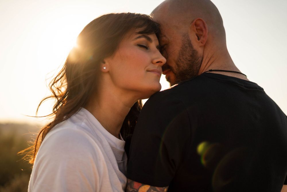 Romantic couple sharing an intimate moment at sunset in golden light with mountains in background.