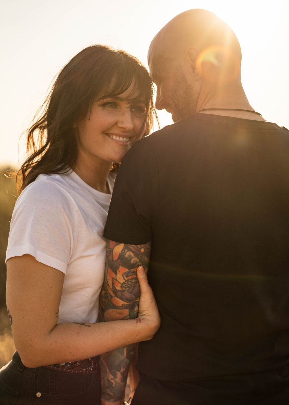 Romantic portrait of couple in casual wear during sunset with warm lighting.
