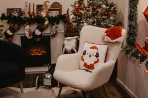 White armchair decorated with Santa pillow near Christmas decorations and stockings.