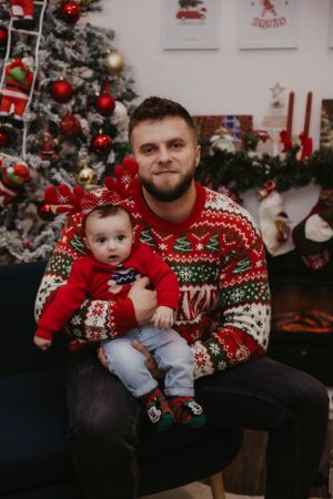 Christmas portrait with festive sweater and decorative trees in background.