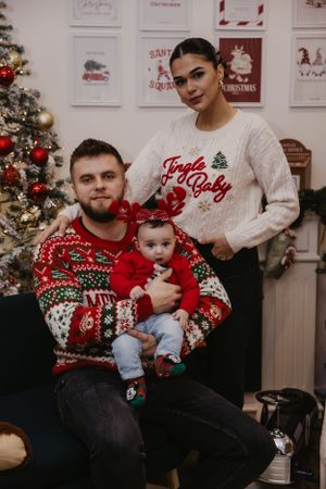 Holiday family portrait with matching Christmas sweaters and festive decor.