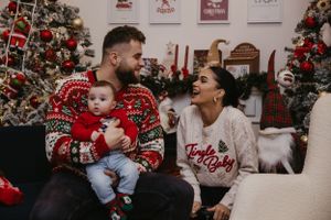 Christmas photo session with festive sweaters and decorated tree backdrop.
