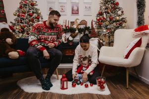 A family gathers near Christmas decorations and lanterns in a cozy living room setting.