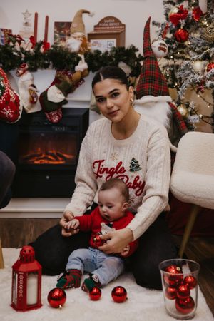 A cozy holiday scene with red ornaments and lanterns by a fireplace with Christmas decorations.