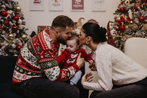 A tender family moment captured in front of a decorated Christmas tree.