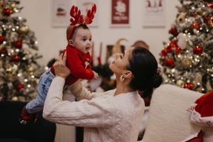 Sweet holiday moment captured with reindeer antlers and Christmas trees in background.