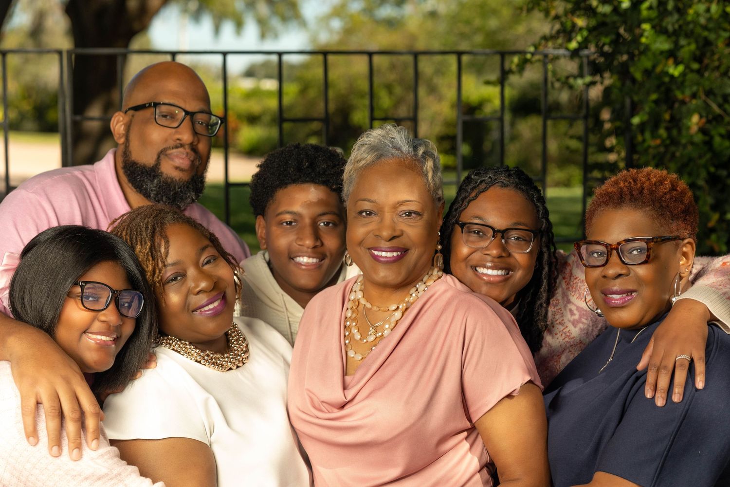 Happy family of six smiling together outdoors in a warm and loving group portrait.