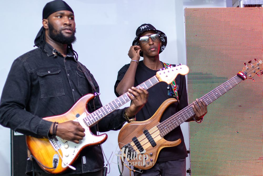 Musicians playing electric guitars during live performance with stage lighting effects.