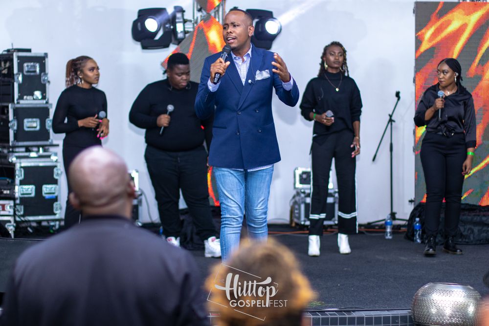 A performer in a navy suit and light jeans delivers an energetic performance on stage.