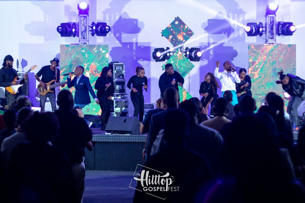 Concert stage illuminated with blue and purple lights while performers entertain a crowd.
