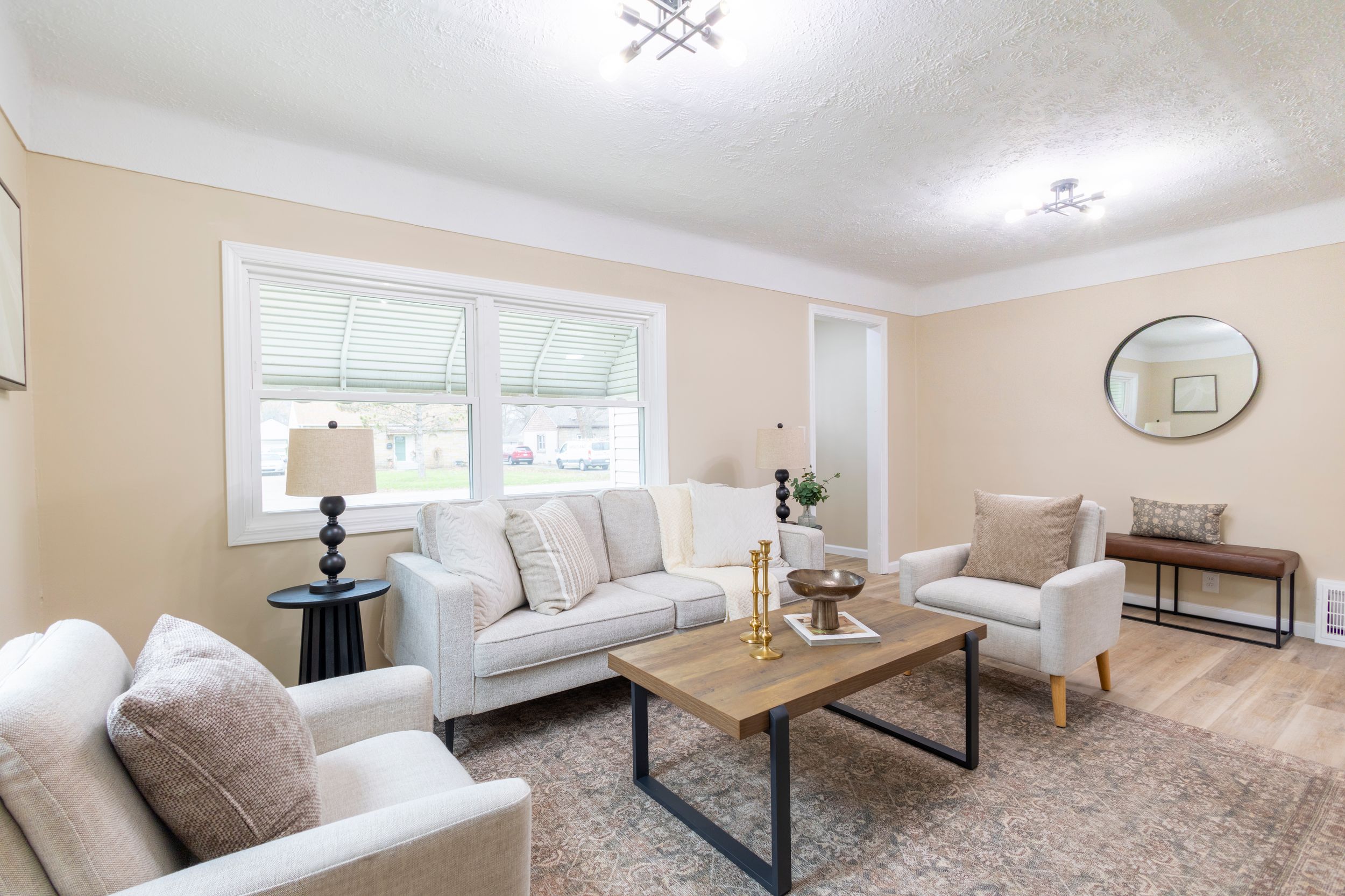 A panoramic view of a modern living room with white walls, beige carpeting, and contemporary furniture.