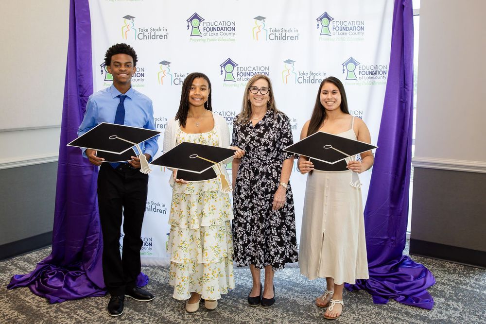 Four scholarship recipients pose with graduation caps at a New Beginnings for Children Foundation awards ceremony.
