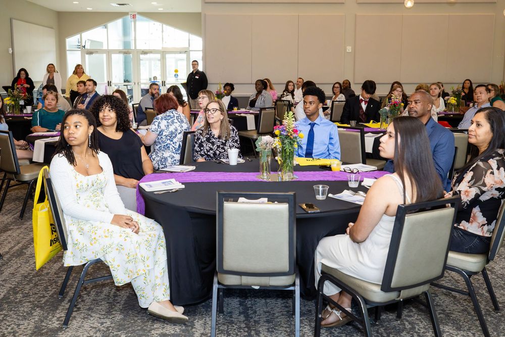 Diverse group of students seated at round tables during a formal banquet event in a bright conference hall.