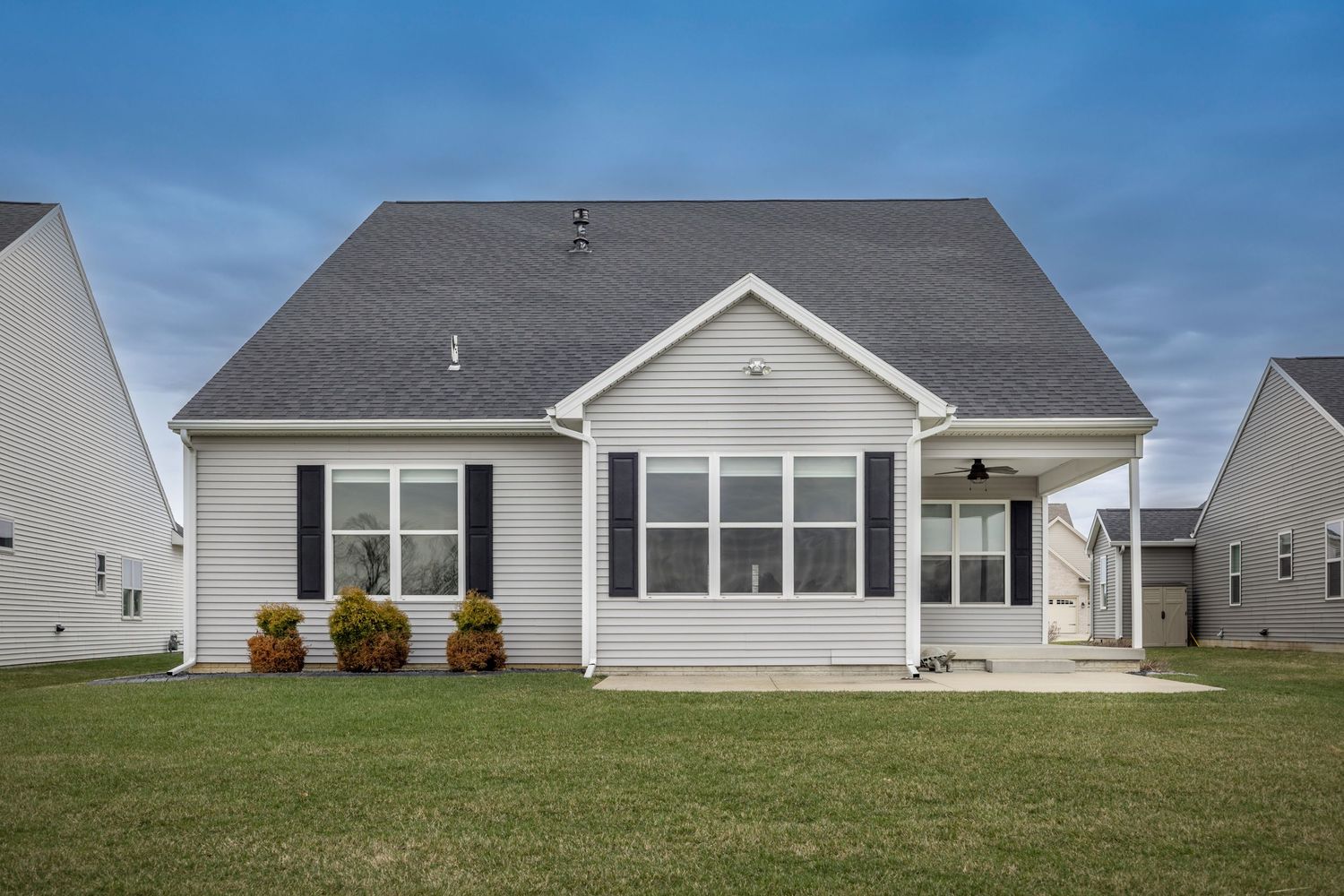 Charming single-story ranch home with gray roof, white siding, black shutters, and a well-manicured lawn.