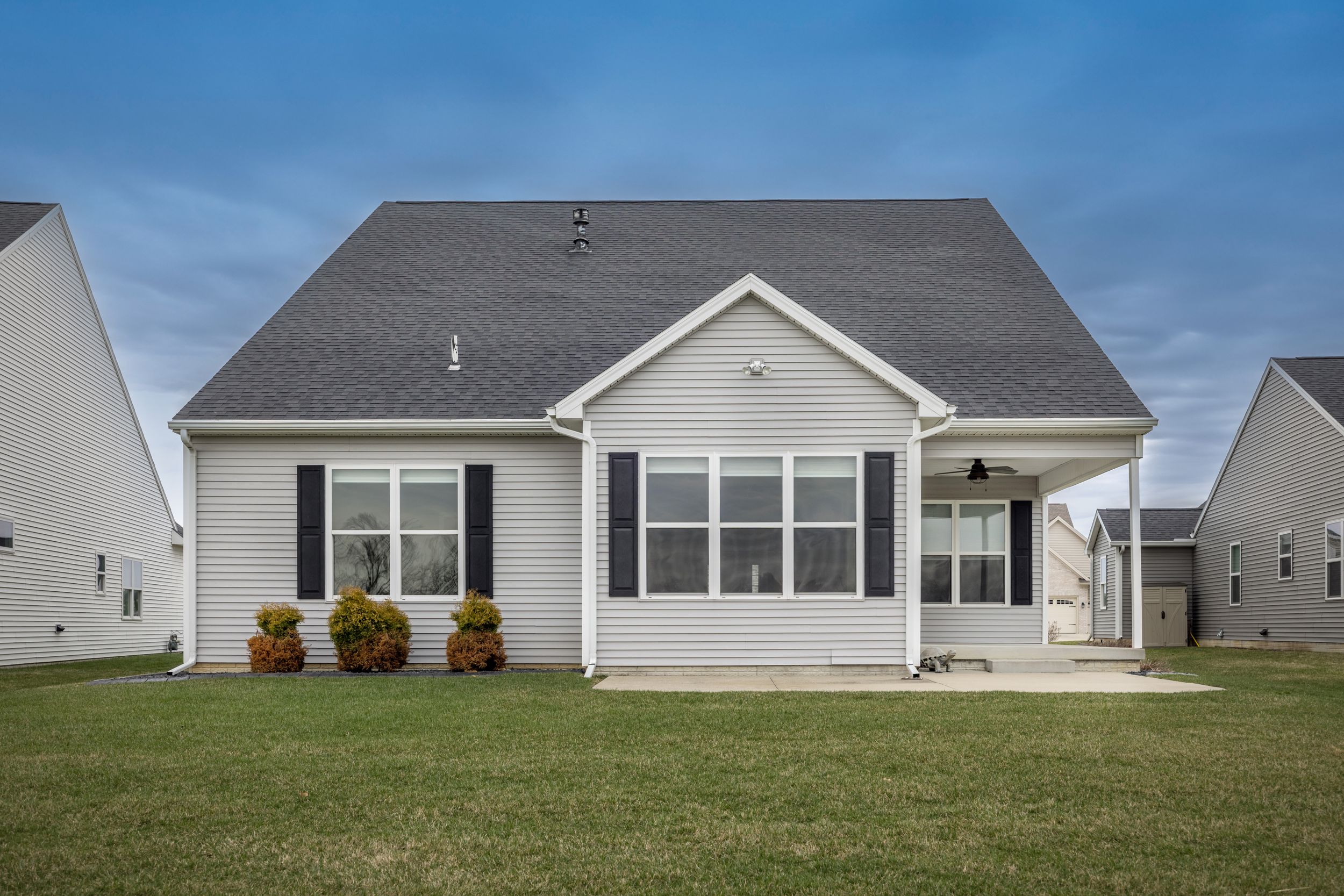Charming single-story ranch home with gray roof, white siding, black shutters, and a well-manicured lawn.