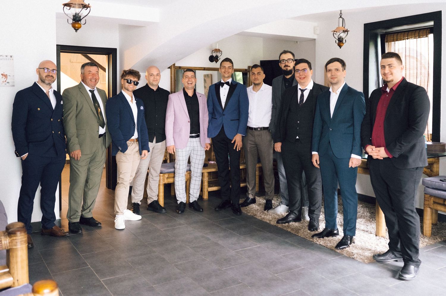 Group of well-dressed men posing together indoors at a formal gathering or wedding celebration.