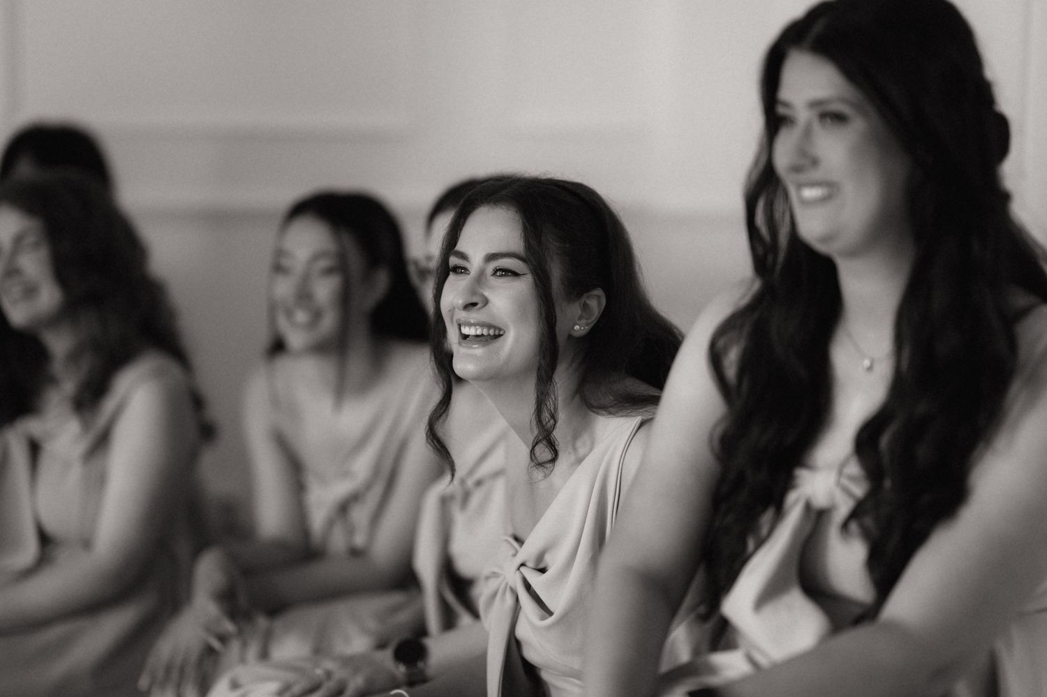 Black and white photo of bridesmaids laughing and smiling together during a wedding preparation moment.