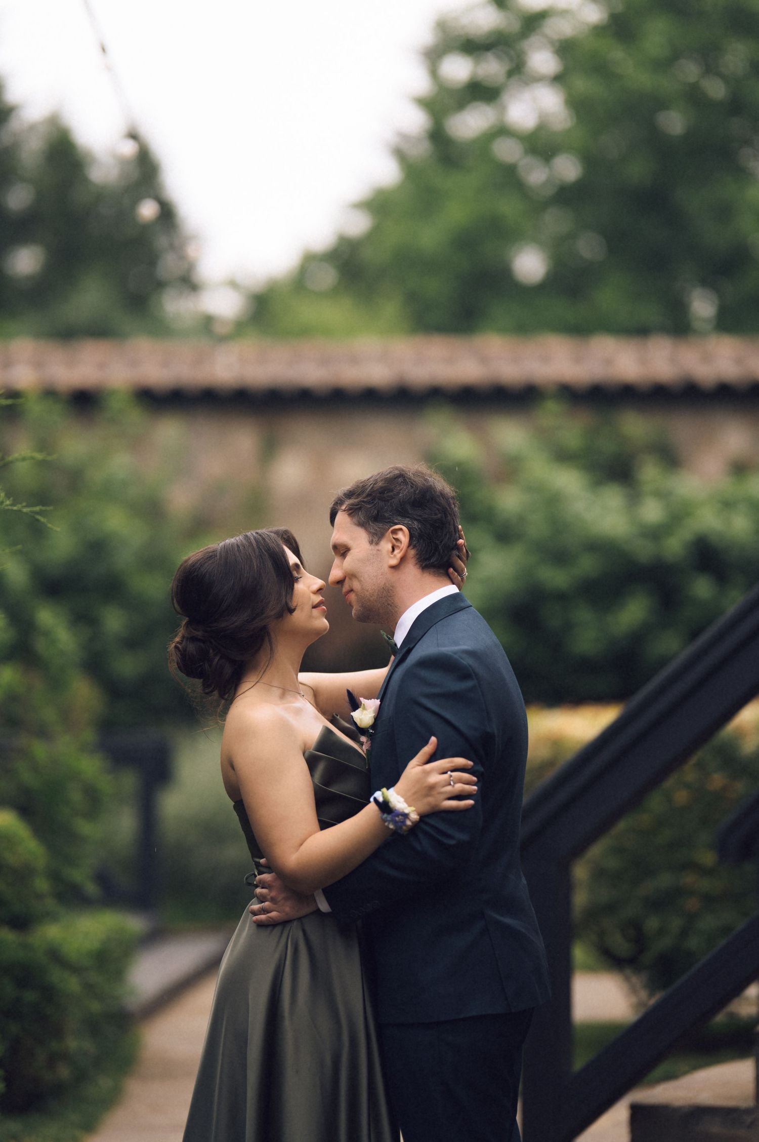 Couple in formal attire sharing a romantic moment in a lush garden setting, perfect for weddings.