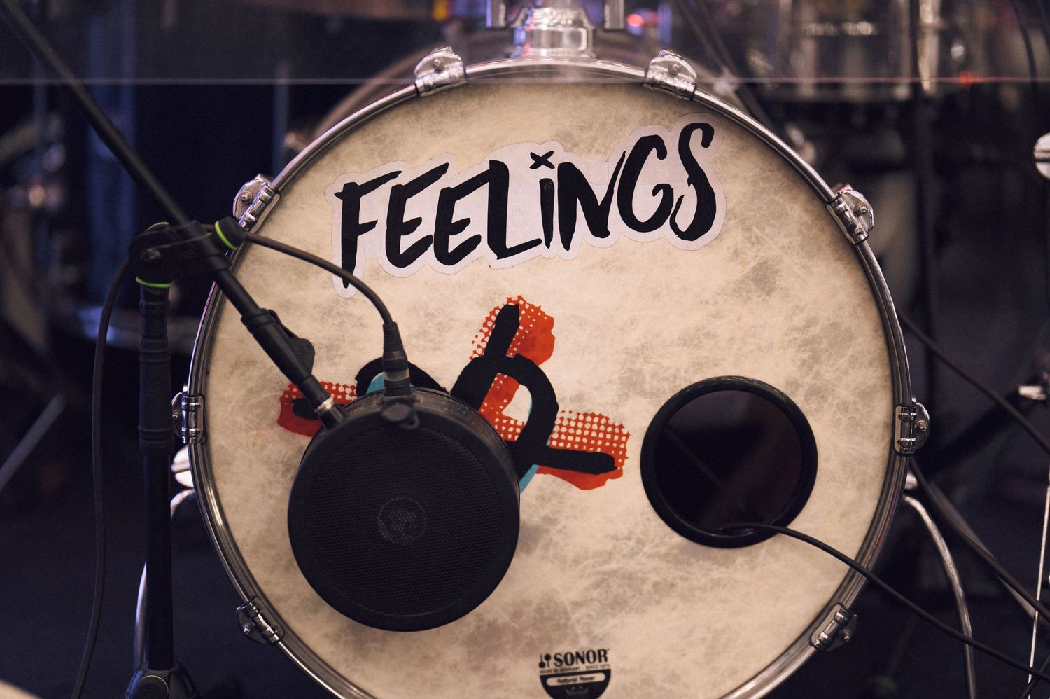 A close-up of a bass drum head with the word FEELINGS written in bold black letters on a white drum skin.