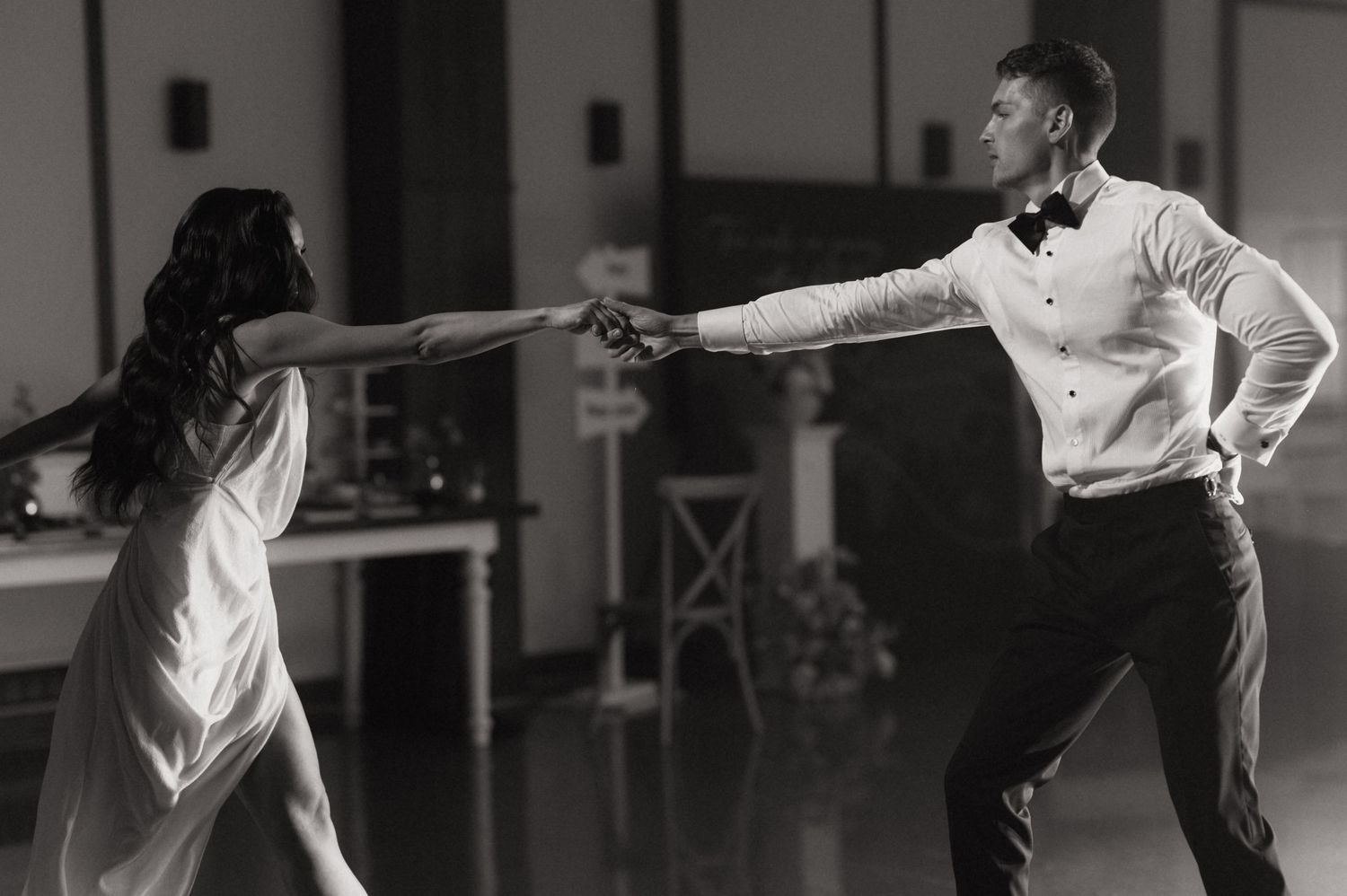 Black and white photo of a couple sharing their first dance at a wedding reception.
