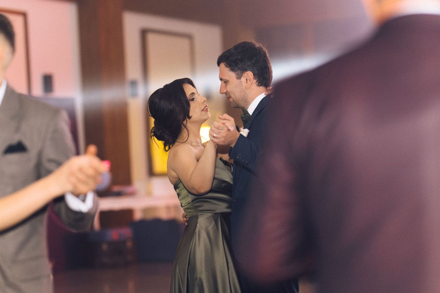 Couple sharing a romantic dance at a wedding reception in elegant formal attire.
