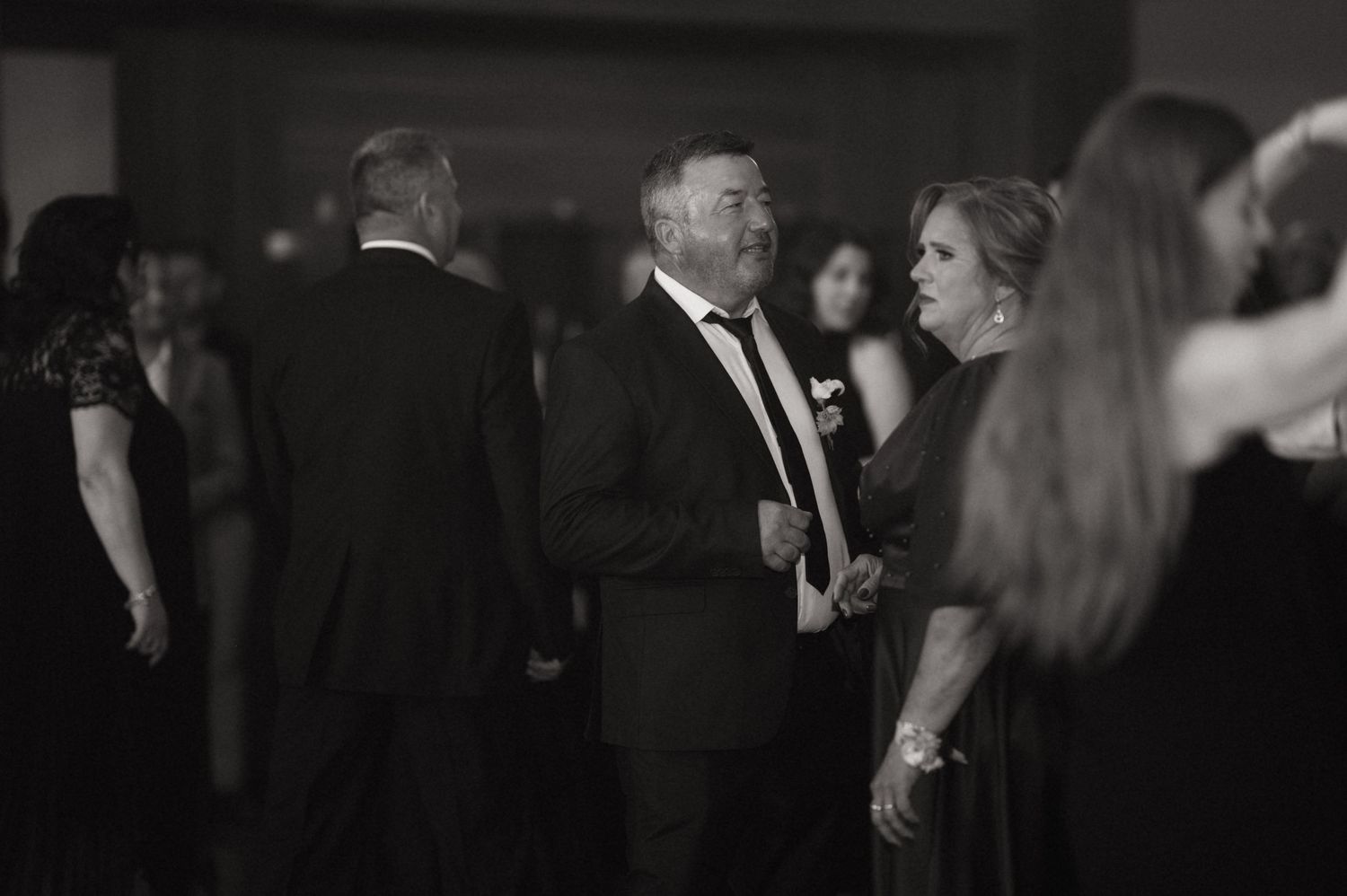 Guests mingling and dancing at a formal black tie event in black and white photo.