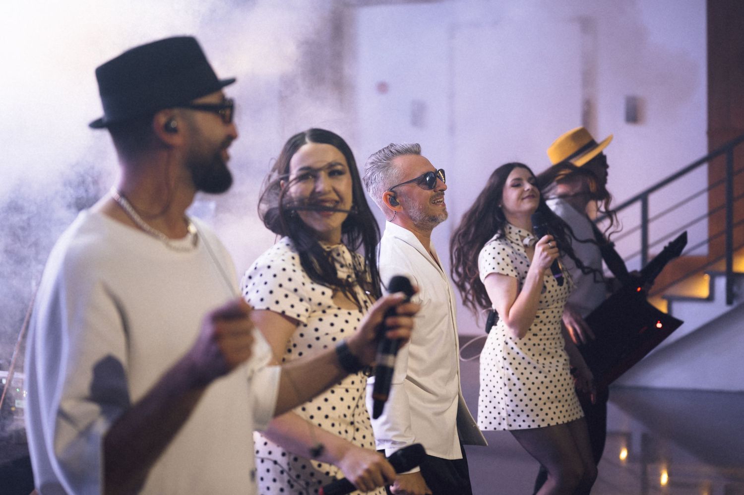 Diverse group of stylish people dancing and socializing at an indoor party with dramatic lighting.