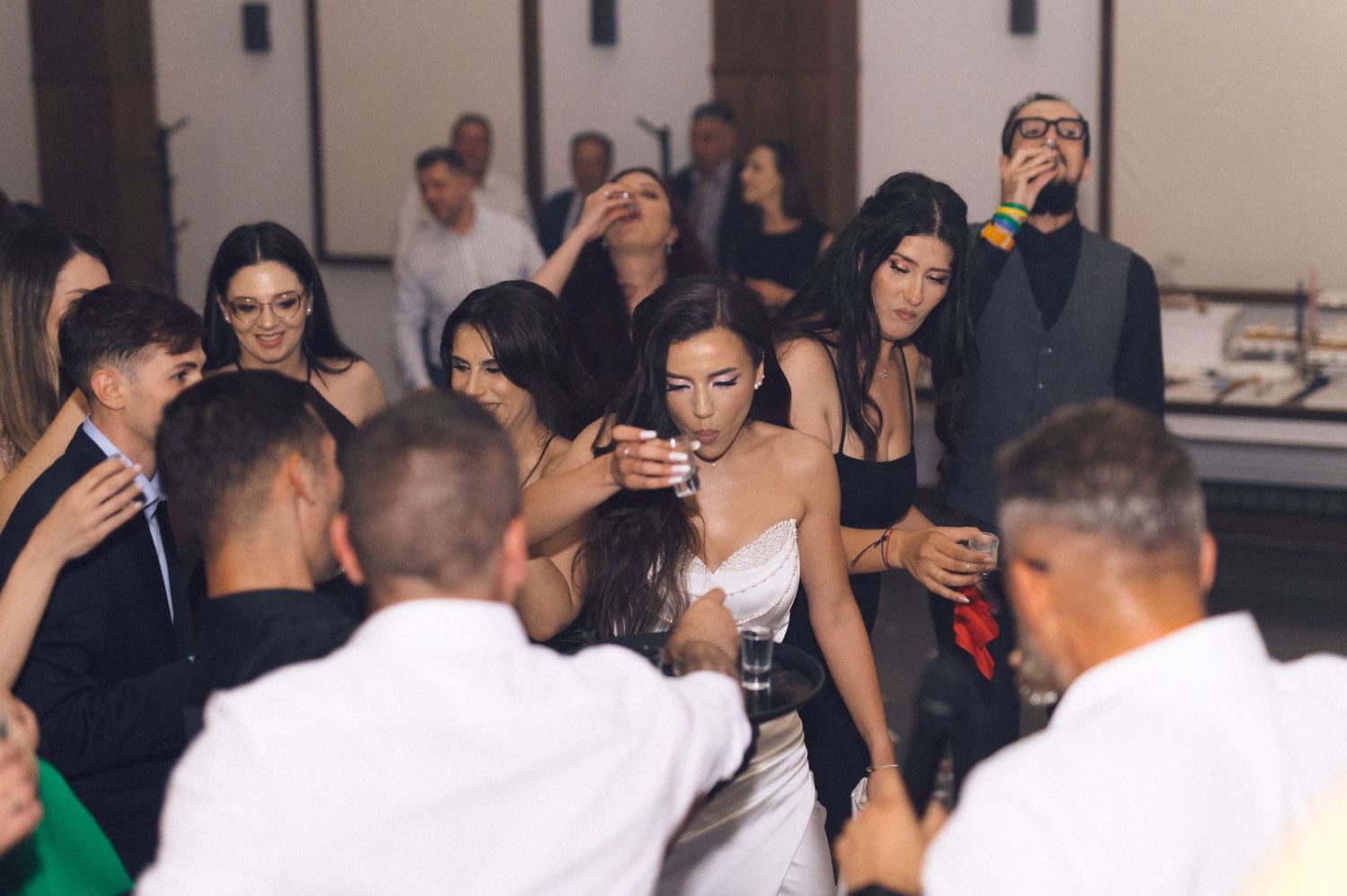 Guests dancing and celebrating at a lively wedding reception party indoors.