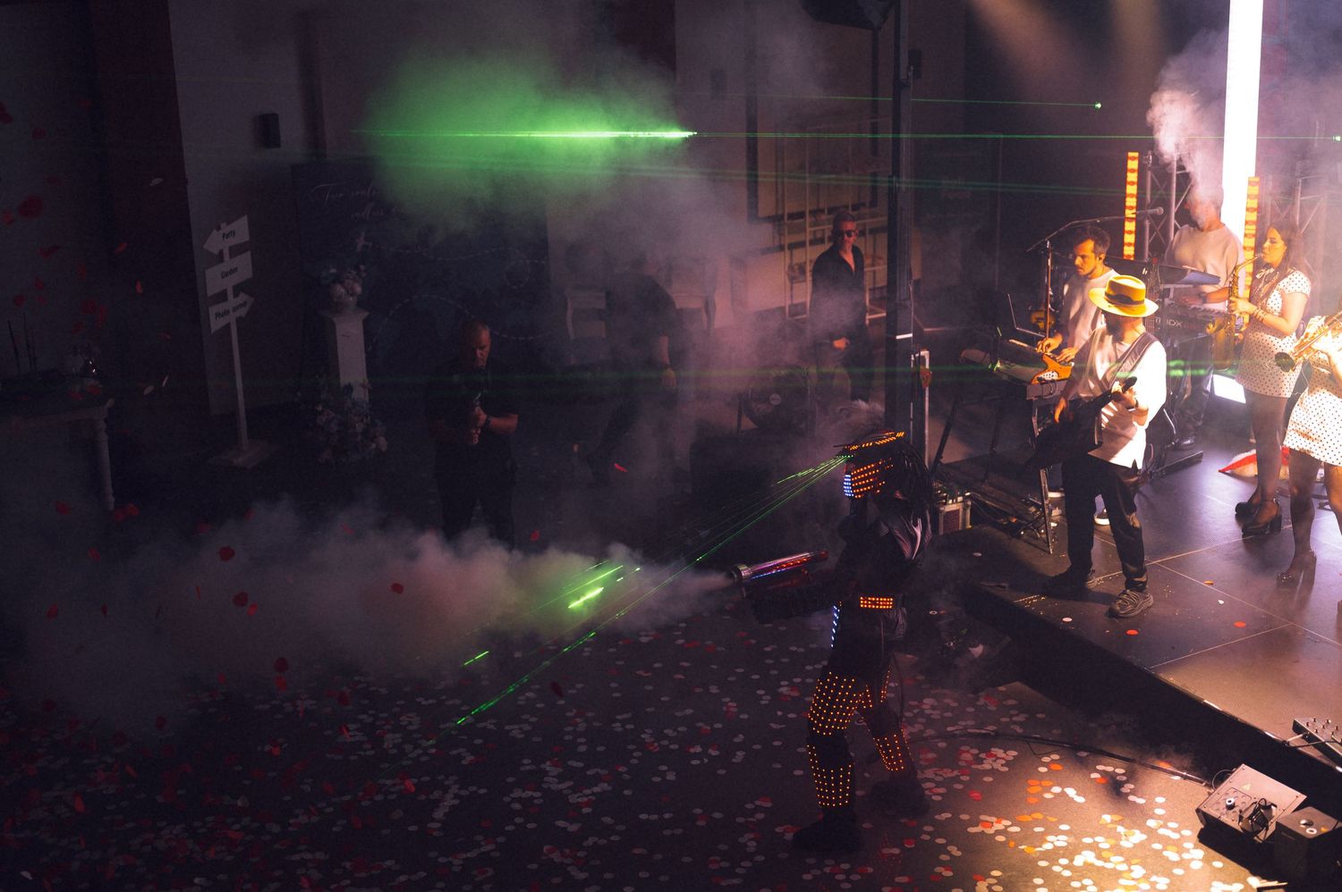 Band performs on stage with green laser lights and smoke effects during a live concert.