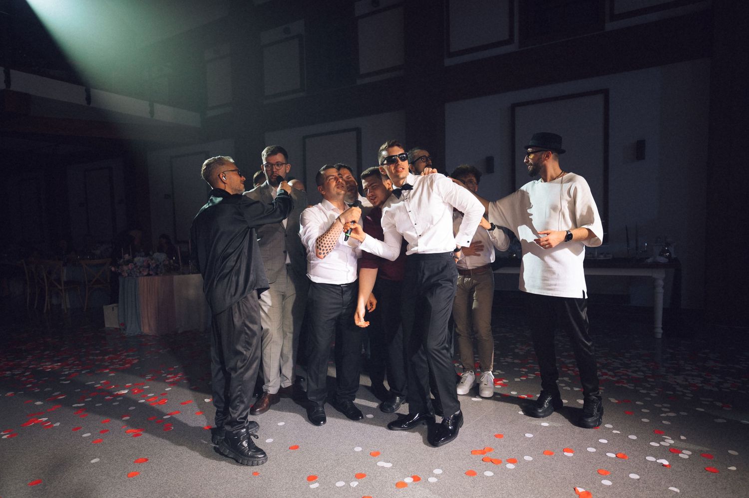 Group of people celebrating on a dance floor with confetti, dressed in formal and chef attire at an event.