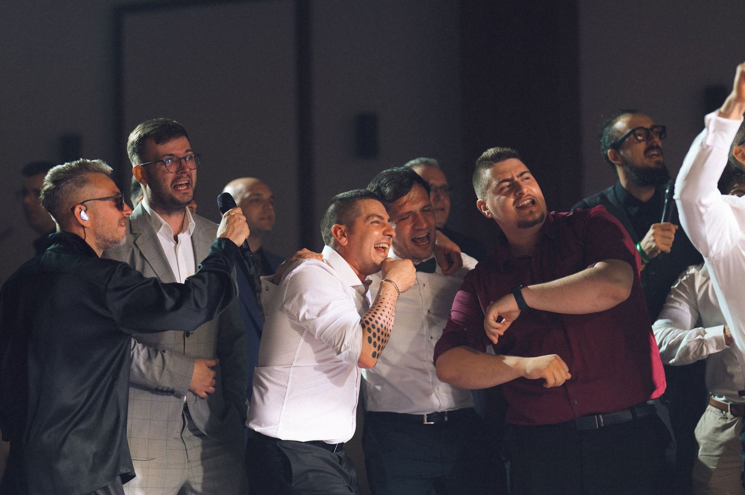 Group of men in formal attire engaged in a heated argument or confrontation indoors.