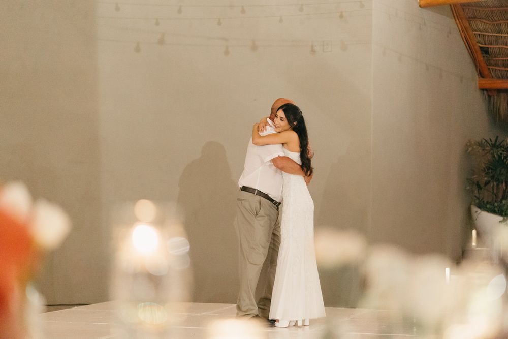 Bride and groom share an intimate first dance embrace in a softly lit wedding reception venue.
