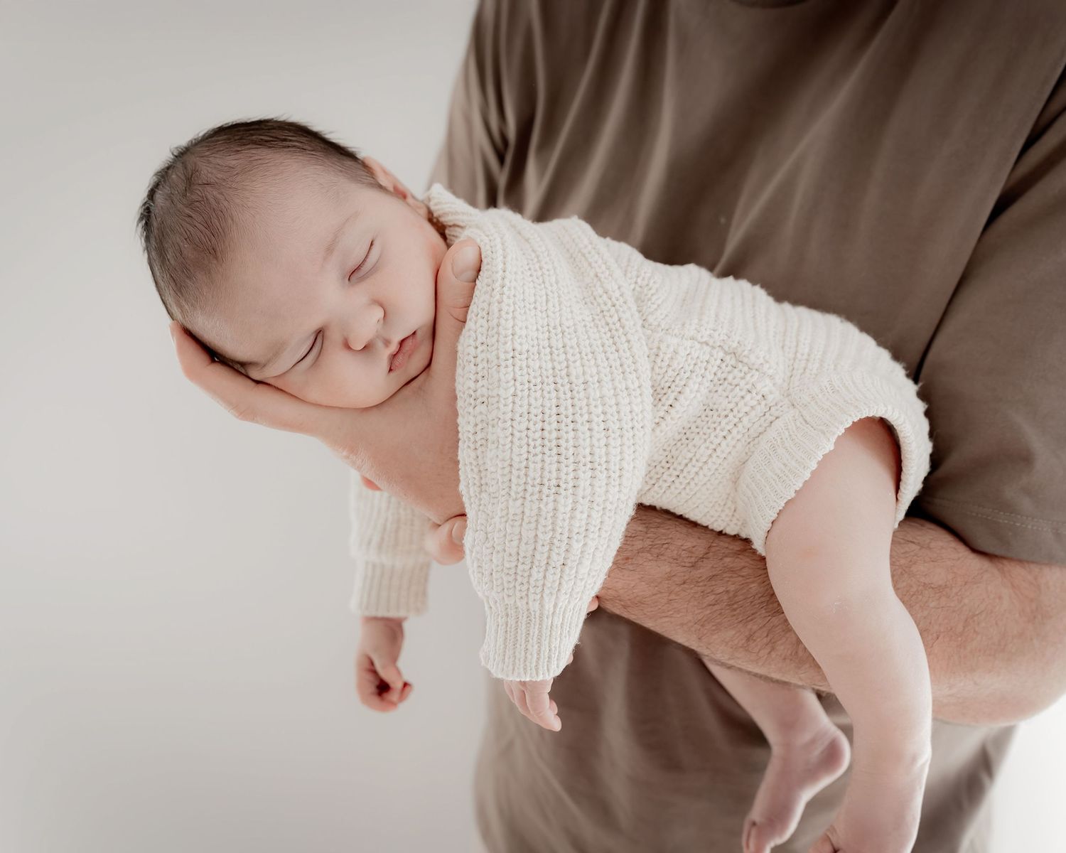 newborn baby held in dads arms during photography session