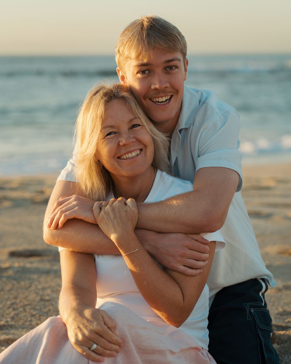 young man hugs his mom from behind on a sunny beach at golden hour photoshoot at Bronte Beach Sydney