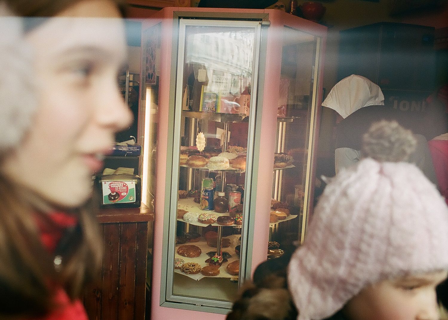 Two children viewing a detailed dollhouse display in a wooden cabinet at a museum exhibit.