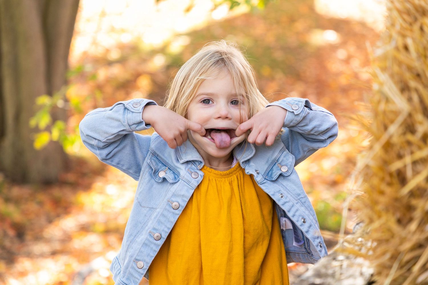 A young girl with her fingers in her mouth and her tongue sticking out
