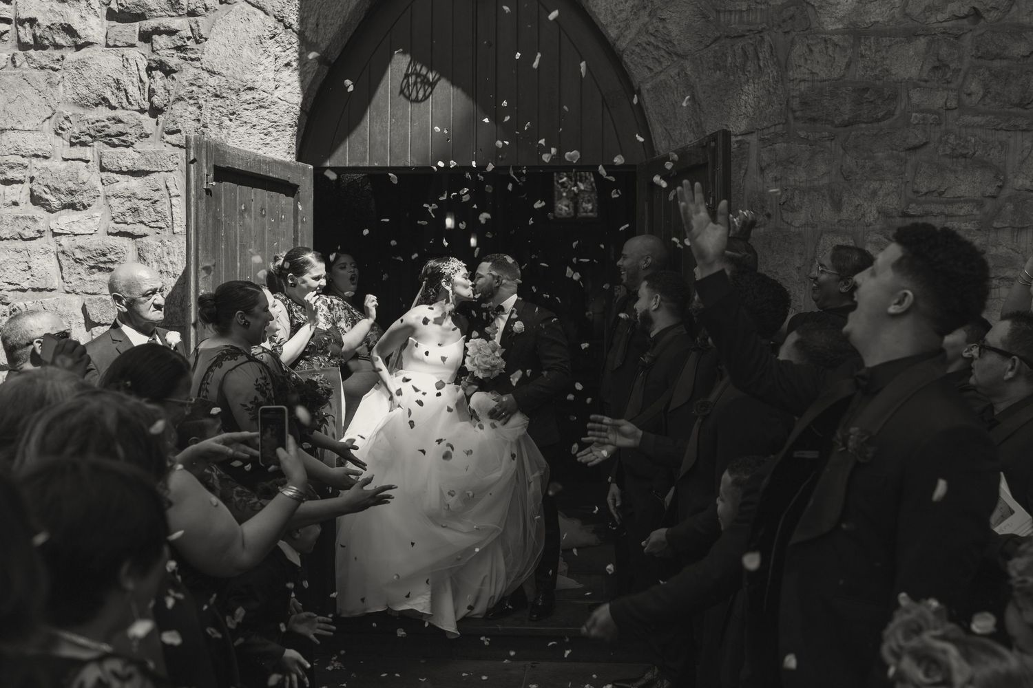 Wedding celebration with confetti being thrown at church entrance.