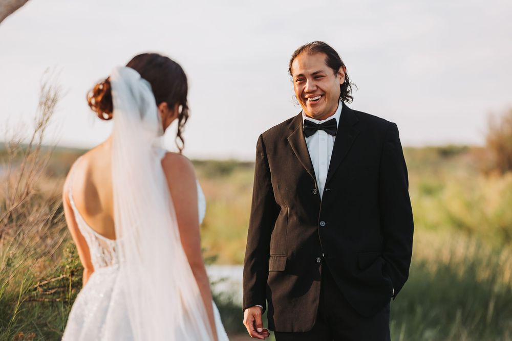 A couple shares a tender moment during their outdoor wedding ceremony in a golden sunlit field.