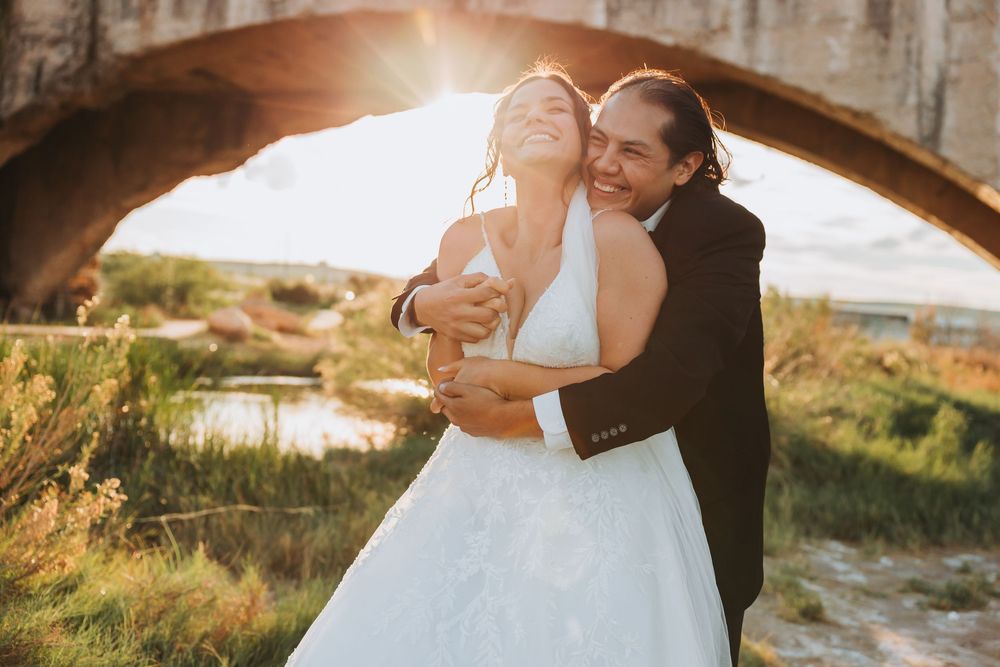 Romantic wedding couple embraces in golden sunset light while photographer captures intimate moments in multiple poses.