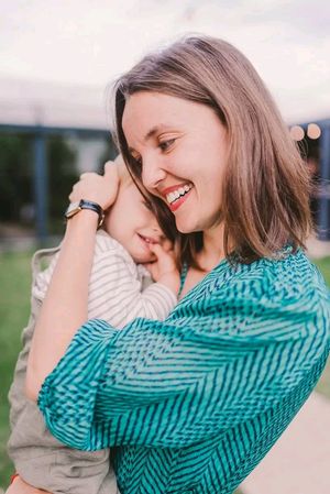 A couple shares an intimate moment of laughter while embracing outdoors in natural lighting.