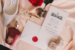 Elegant wedding stationery displayed on blush pink fabric with red accents.