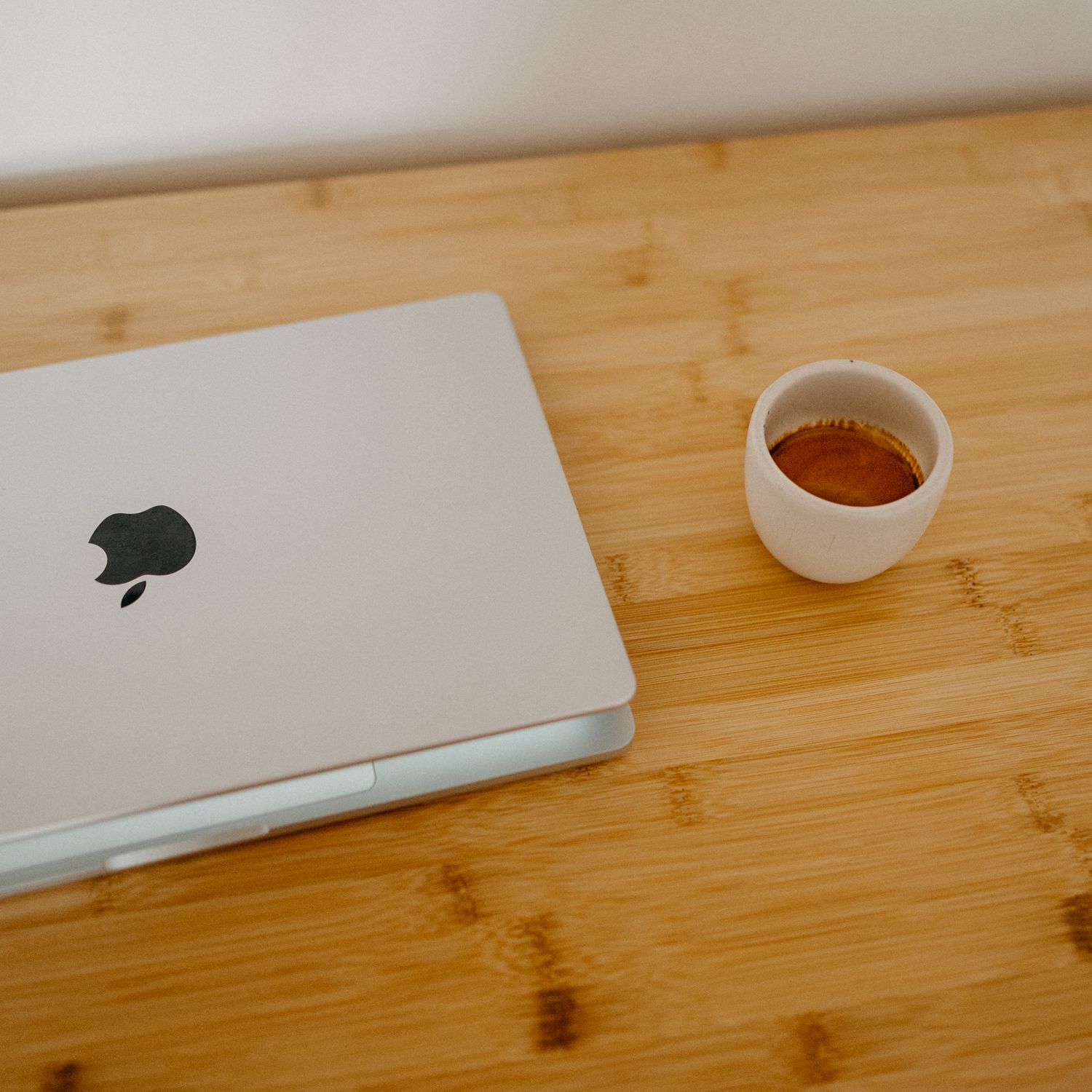 White Apple Magic Mouse and keyboard on bamboo wooden desk surface with orange tea light candle in glass holder.