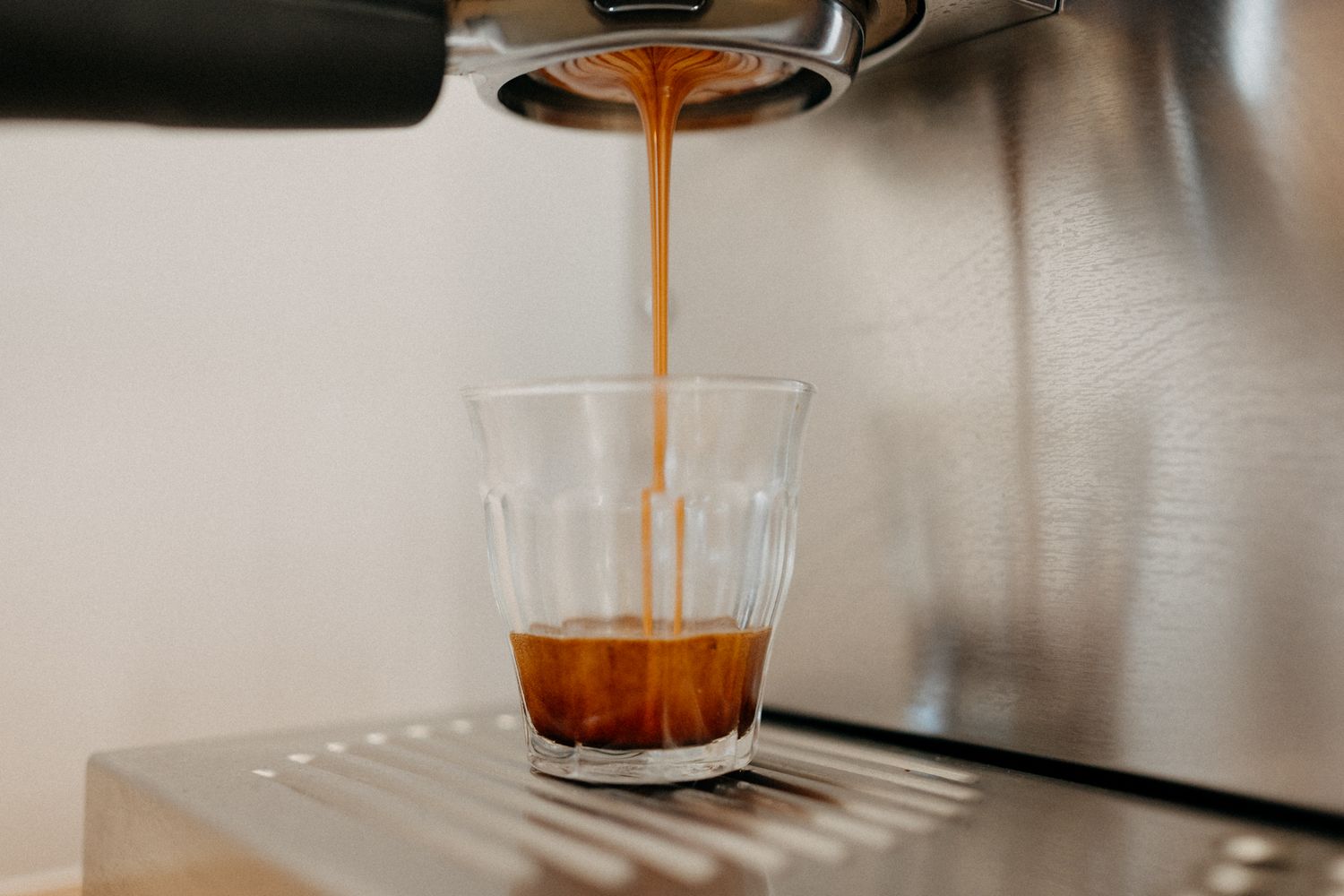 Coffee being poured into clear glass creating artistic stream.