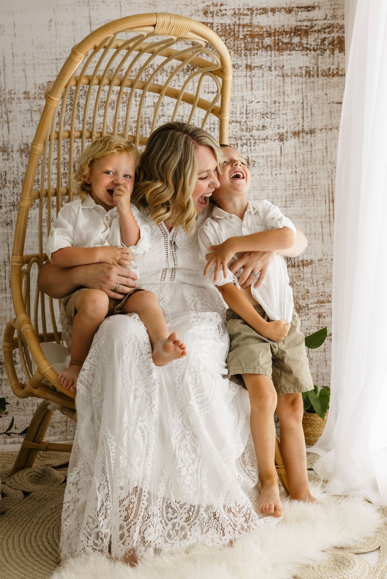Mom dressed in white as she laughs with your young boys during a mommy and me session at Somerset Portraits' Charlottesville studio.