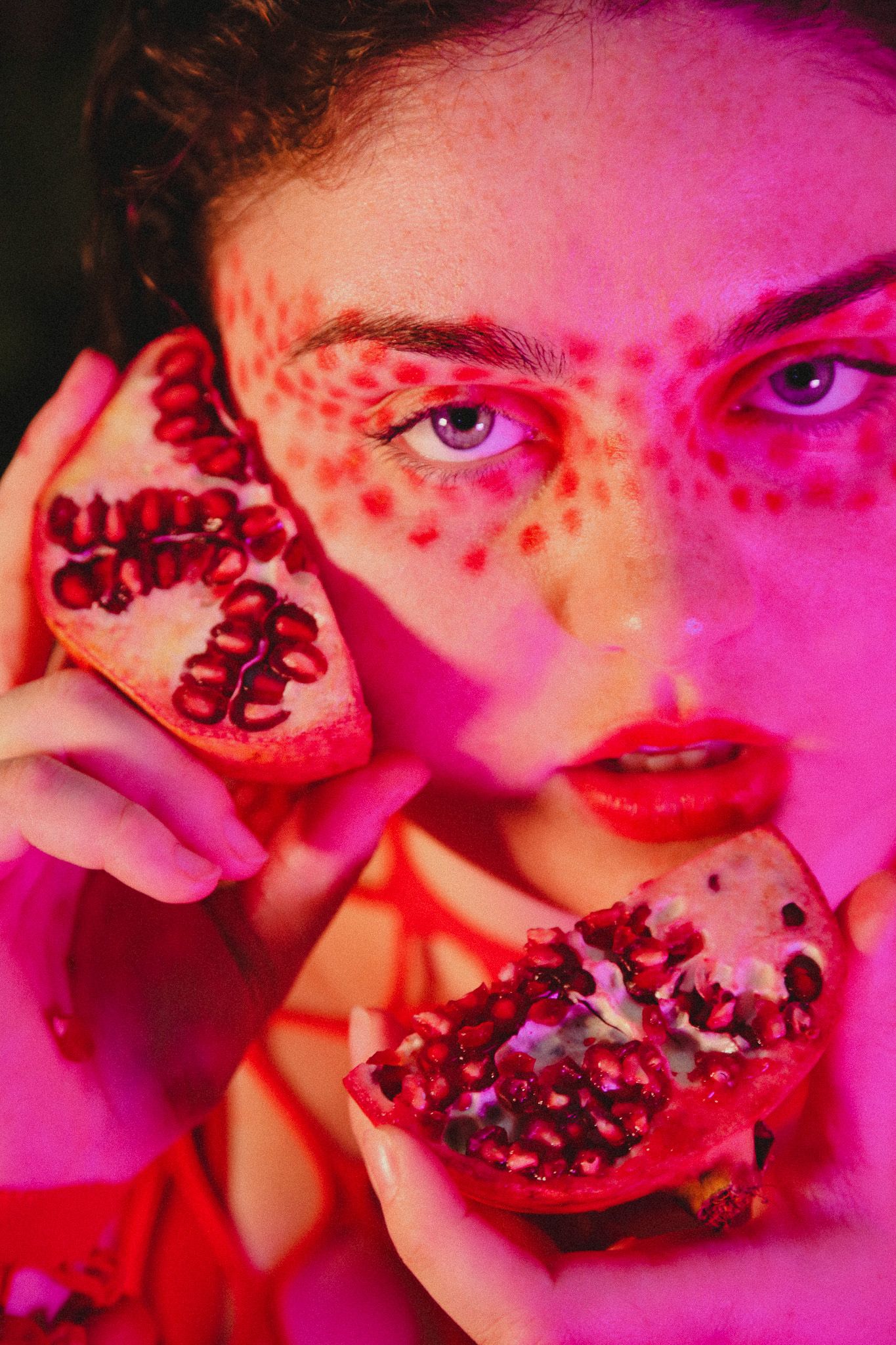 Artistic photo series showing pomegranate fruit held against pink lighting with dramatic shadows and close-up details.