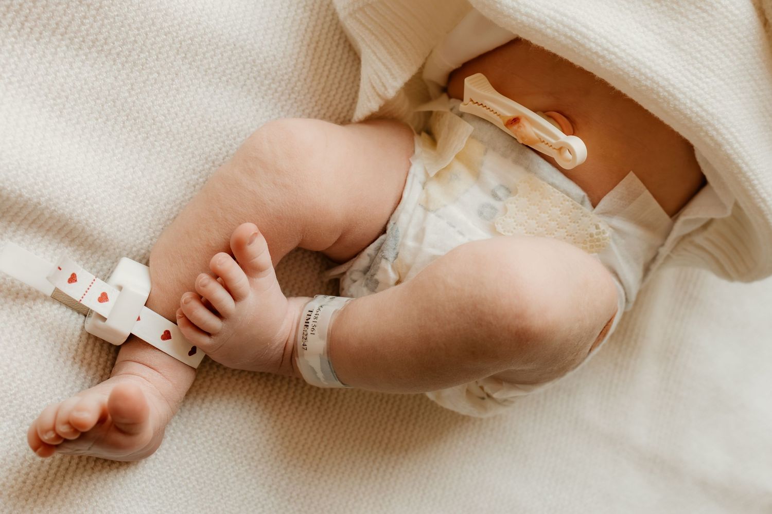 Delicate newborn feet and toes wrapped in soft white blanket.